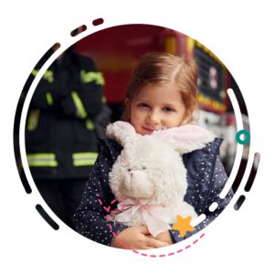 fire safety: girl holding stuffed bunny in front of firetruck