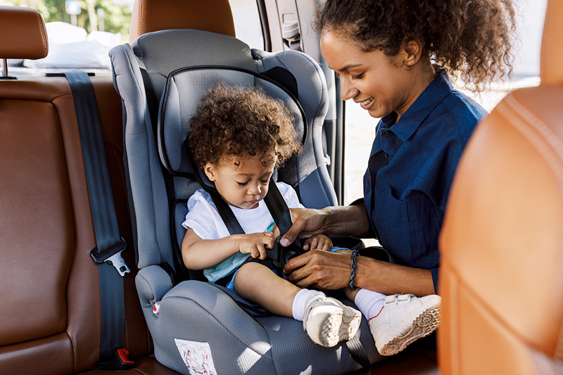 mom buckling child in a car seat